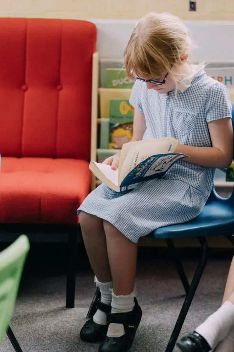 Young girl reading a book in a primary school classroom, illustrating a focus on early education at St Katharines Primary School.