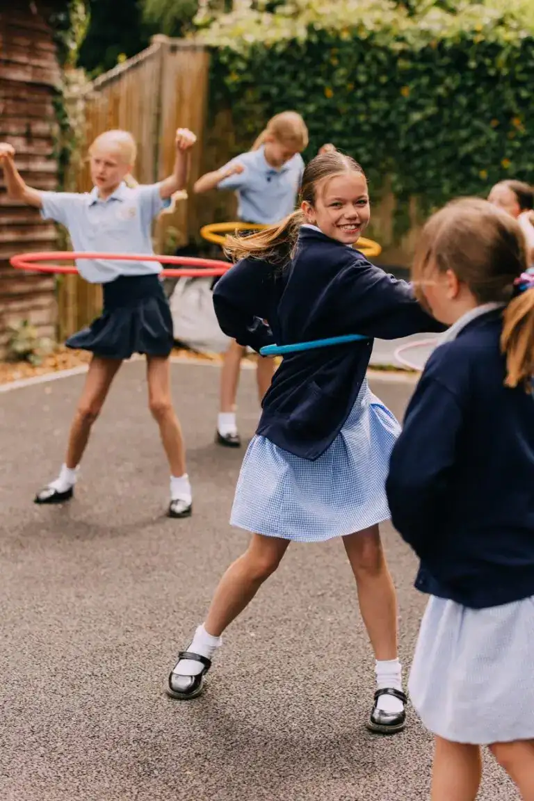 Children playing with hula hoops at St Katharines Primary School in Knockholt, Kent, showcasing a joyful outdoor activity for early childhood education and physical development.
